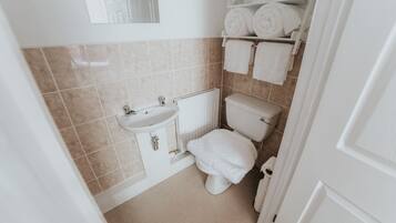 A small, clean bathroom with a toilet, sink, and towel rack.