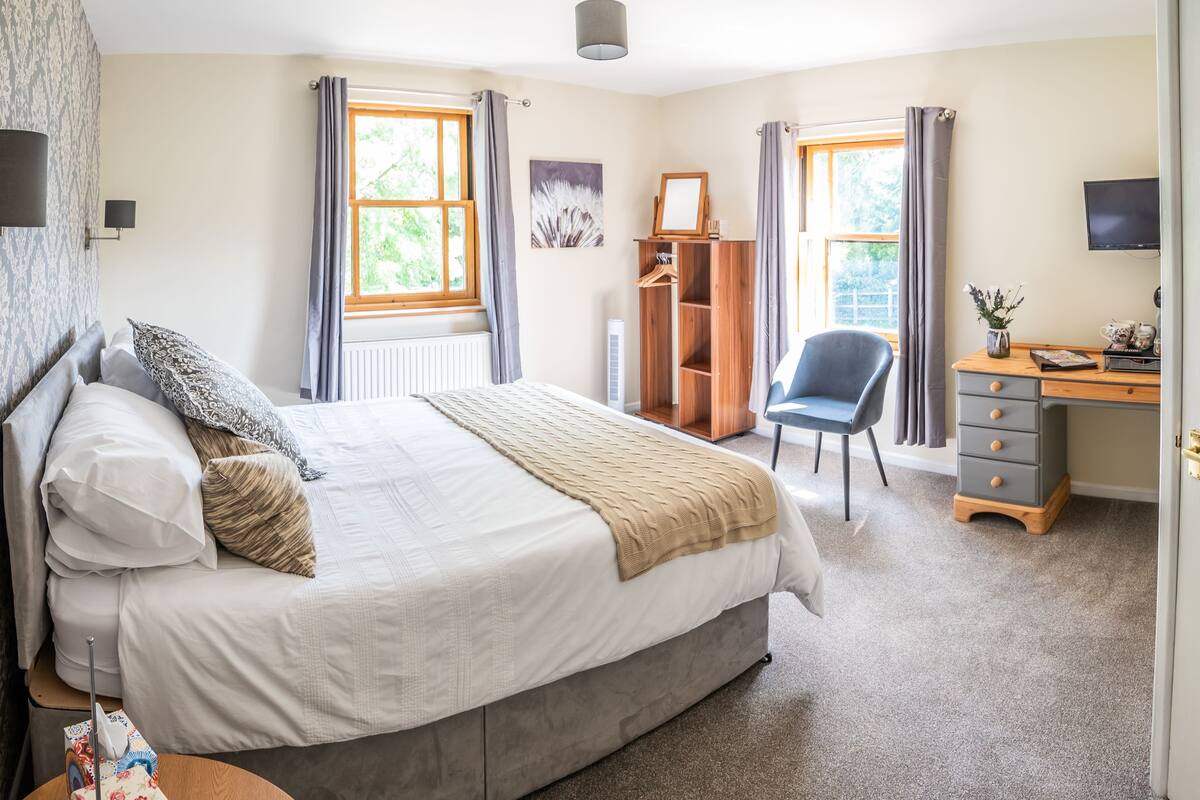 Une chambre à coucher comprenant un lit, une table de chevet, une commode, une chaise et un bureau avec une autre chaise.