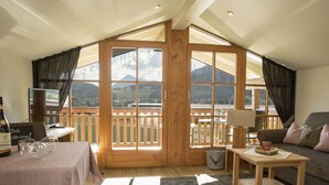 Ein gemütliches Zimmer mit Esstisch, Sofa und Balkon mit Bergblick.