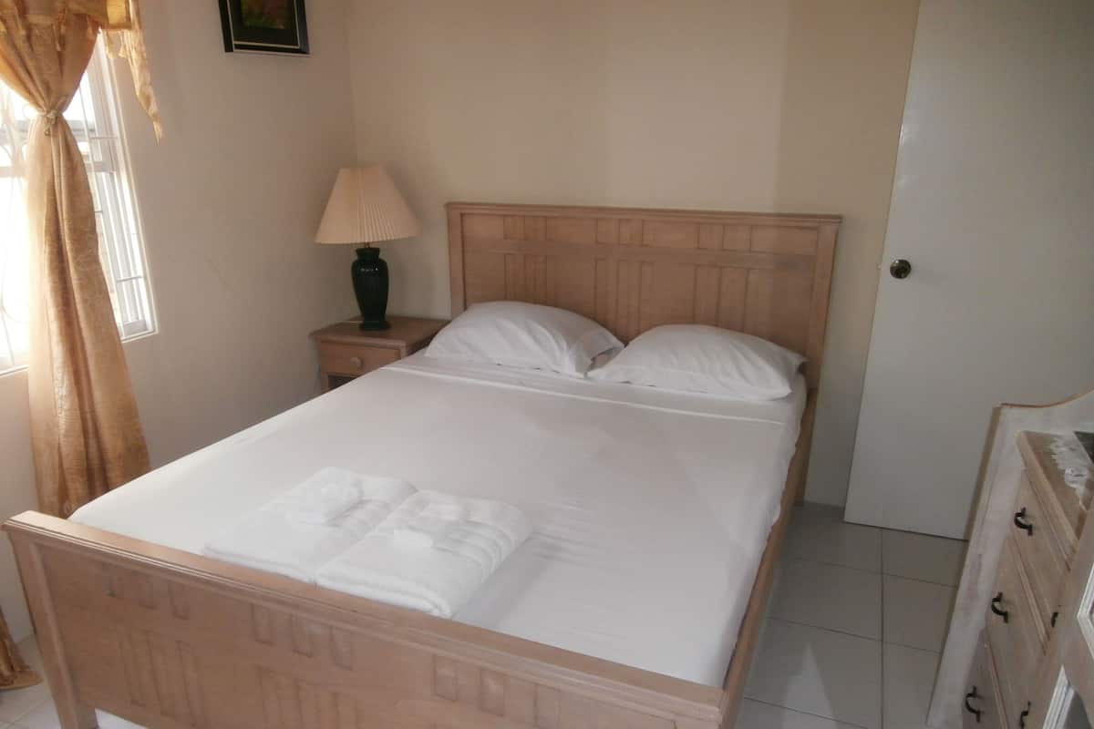 A neatly made bed with white linens and a folded towel on the footboard.