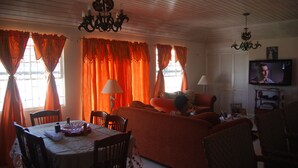 A living room with a sofa, chairs, a dining table, and a TV. - Sue'S Homestay (Oistins)