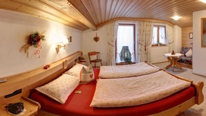 A cozy room with two beds, a wooden ceiling, a small table, and a window with curtains. - Ferienwohnung Martina für 5 Personen, 3 Schlafzimmer mit Balkon, 90 m² (Inzell)