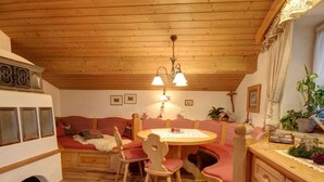 A cozy room with a wooden ceiling, a round wooden table with chairs, a sofa, and a small cabinet. - Ferienwohnung Martina für 5 Personen, 3 Schlafzimmer mit Balkon, 90 m² (Inzell)