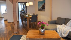 Een moderne woonkamer met een houten salontafel, een bank en een eethoek met stoelen en een tafel.