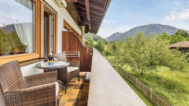Un balcon doté de meubles en osier, d’une table et offrant une vue sur les montagnes.