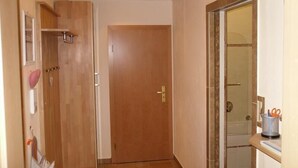A hallway with a wooden door, a mirror, and a small shelf with a heart-shaped decoration. - Exclusive vacation apartment with mountain view, 50sqm, 1 bedroom, winter garden (Bad Reichenhall)