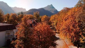A mountain landscape with autumn foliage, a pathway, and a building with a red roof. - Exclusive vacation apartment with mountain view, 50sqm, 1 bedroom, winter garden (Bad Reichenhall)