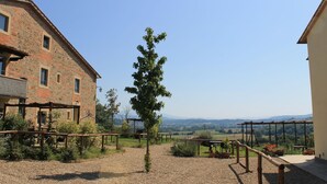 Un patio con sendero de grava, pérgola de madera y un edificio de fachada de piedra.
