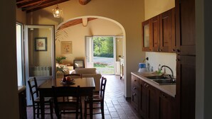 Una cocina con armarios de madera, una mesa de comedor con sillas y vistas al exterior a través de una puerta abierta.
