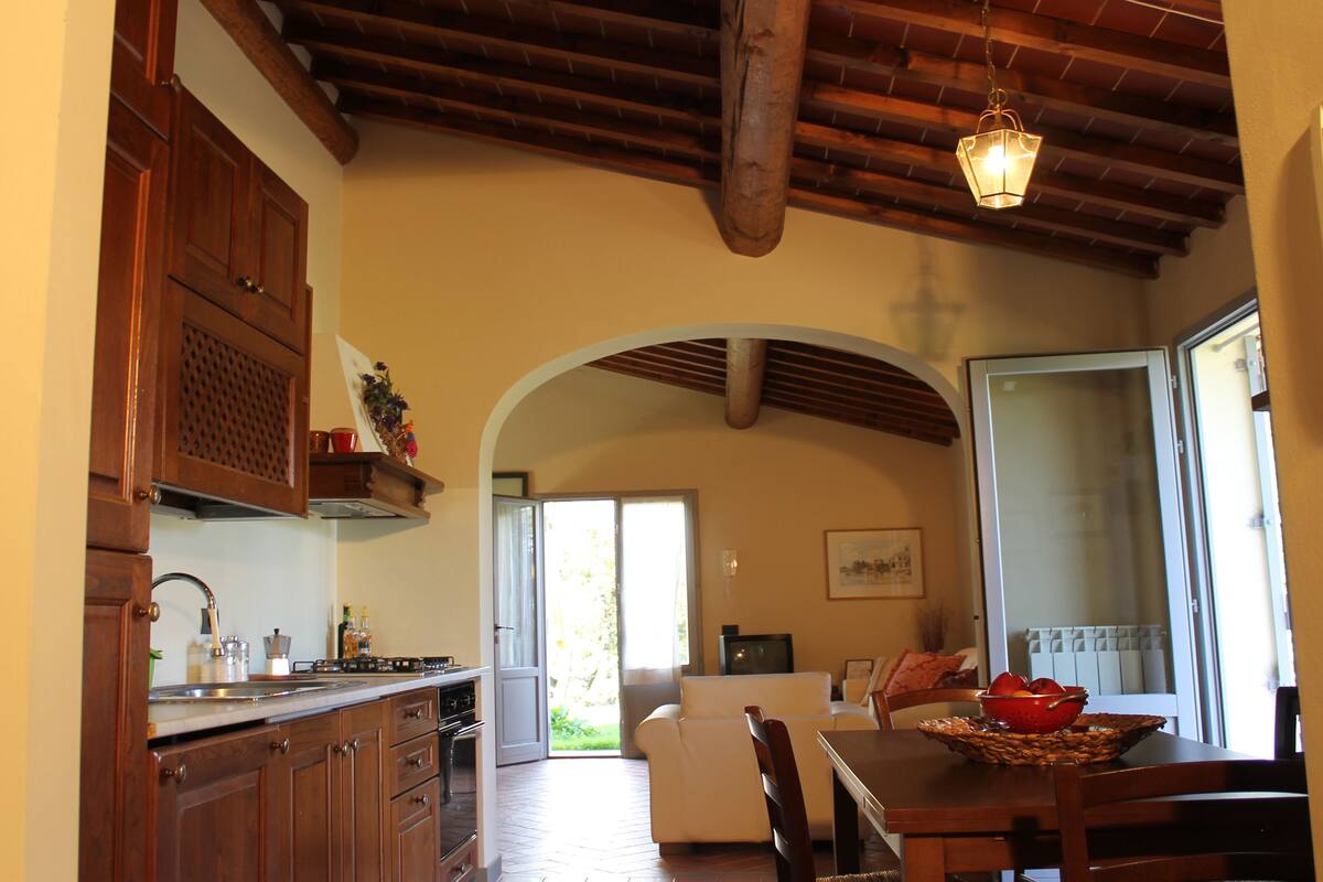 Una cocina con armarios de madera, una mesa de comedor con sillas y un ventanal grande.