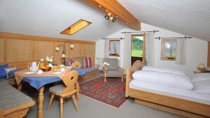 Quarto aconchegante e bem iluminado, com uma mesa posta para o café da manhã, um sofá, uma cama e vista para o exterior.