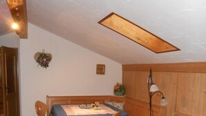 Uma sala de estar acolhedora com uma mesa de jantar, cadeiras de madeira, um sofá e um tapete estampado.