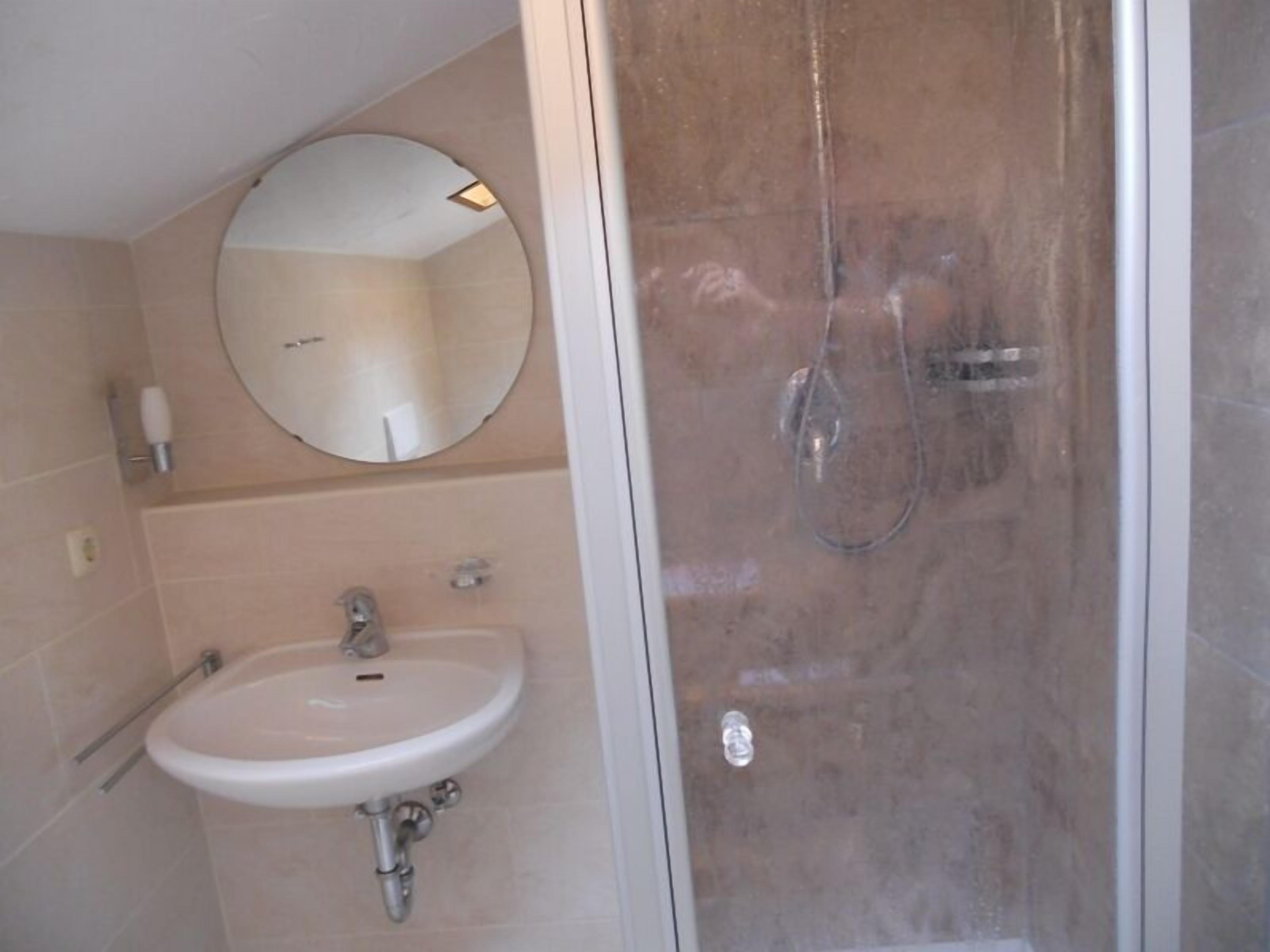 Une salle de bain avec un lavabo, un miroir et une douche.