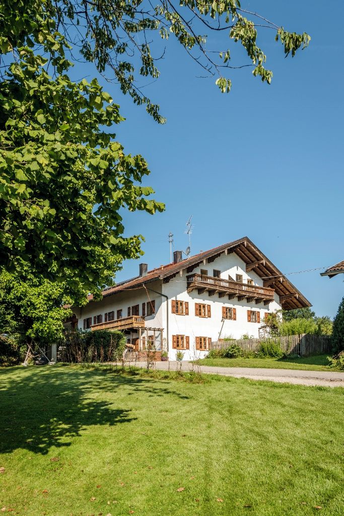Eine zweistöckige Chalet mit geneigtem Dach, Holzbalkonen und einem gepflegten Rasen.