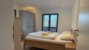 Une chambre à coucher avec un lit en bois, une table de chevet, une armoire et une fenêtre donnant sur des arbres.