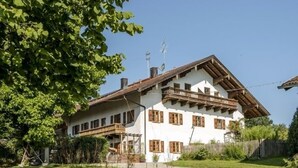 A two-story chalet with a sloped roof, wooden balconies, and a well-maintained lawn. - Vacation apartment Hartsee 52sqm, 2 bedrooms, fireplace, balcony (Eggstätt)