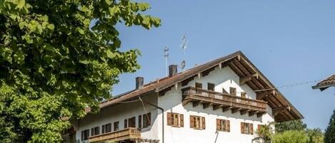 A two-story chalet with a sloped roof, wooden balconies, and a well-maintained lawn.