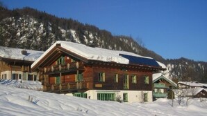 Een houten chalet met schuin dak, meerdere ramen en een balkon.