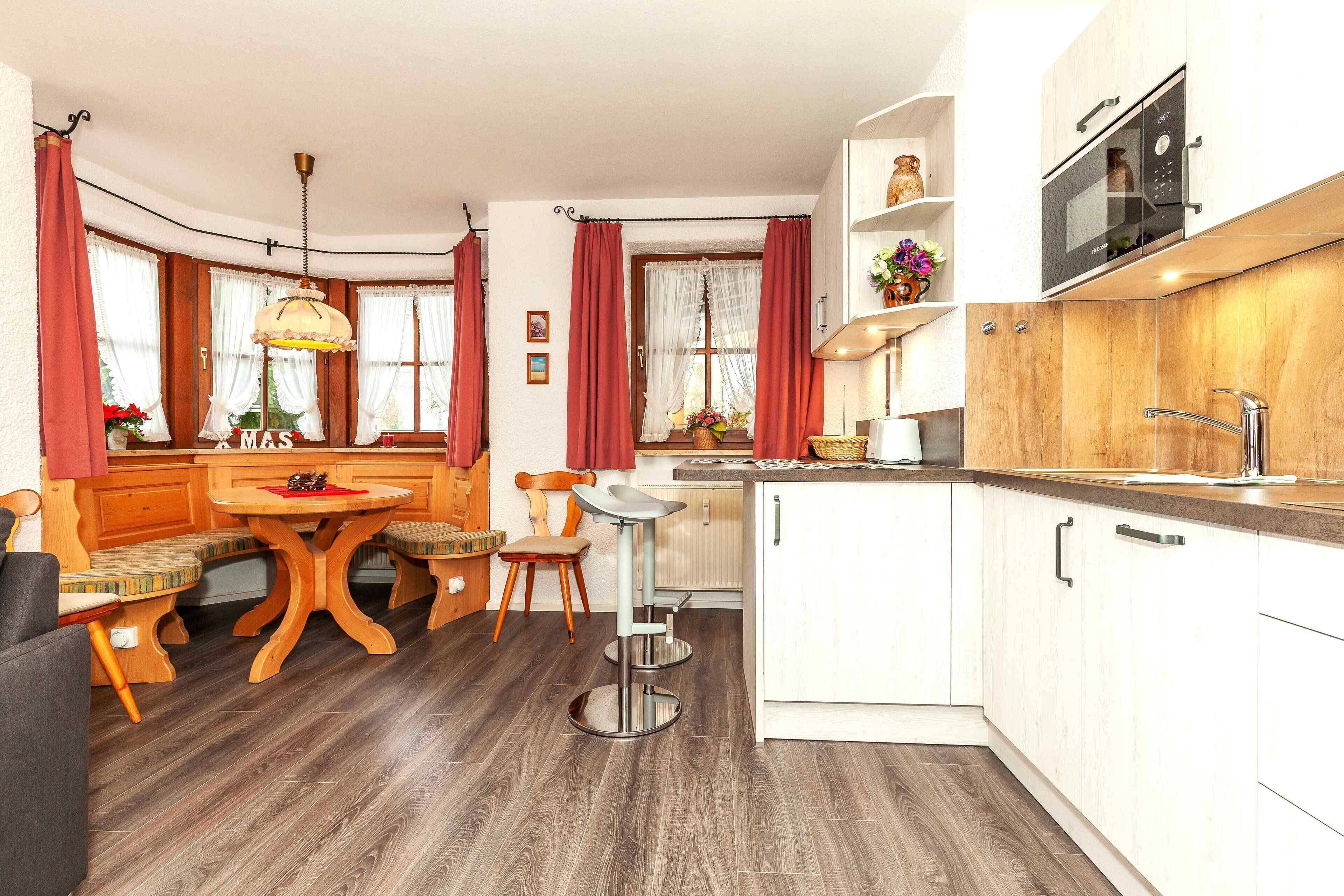 A compact kitchen with a dining area, wooden flooring, and a built-in oven.