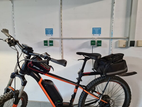 Uma bicicleta de montanha com quadro preto e laranja, selim preto e uma bolsa preta fixada na parte traseira.