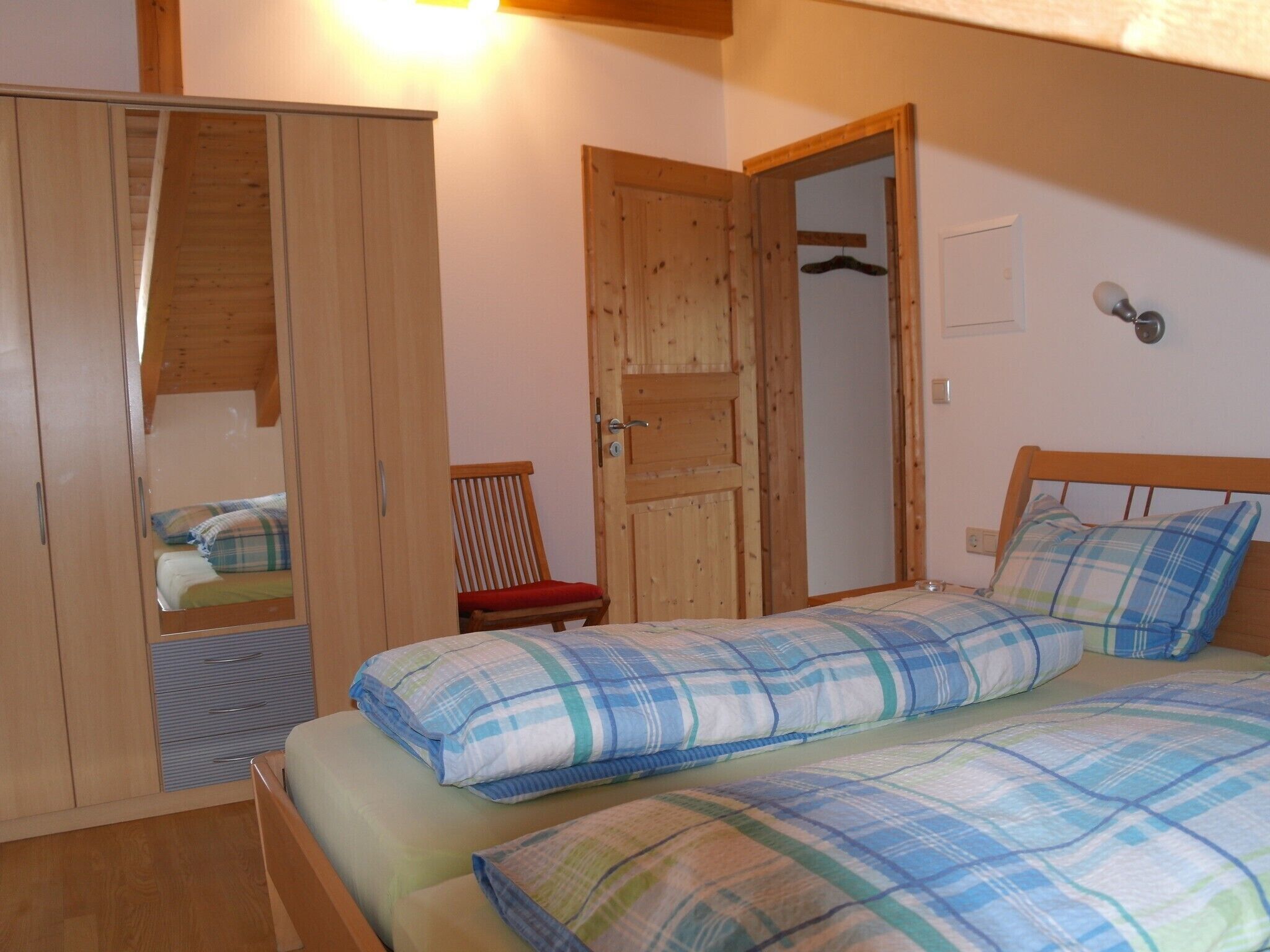 Un dormitorio con cama, armario y una silla.