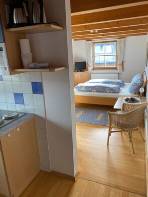 Une pièce confortable avec un lit, une télévision et un coin repas équipé de chaises en osier.
