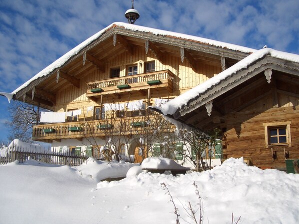 A wooden chalet with a balcony, surrounded by snow. - Vacation room Ramsau 20 sqm 2 persons, bed-sitting room, terrace (Piding)