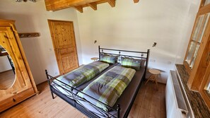Quarto com estrutura de cama de metal, duas camas, guarda-roupa de madeira e porta de madeira.