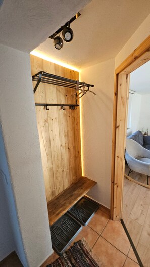 A wooden interior with a bench, a wall-mounted rack, and a door leading to another room. - Komfortable Ferienwohnung, 85 qm, 2 sep. Schlafzimmer und Küche (Reit im Winkl)