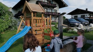 A playground with a slide and climbing structure, surrounded by a grassy area and a building with balconies. - No. 2 Holiday apartment Hörndlwand 70sqm, balcony, 2 bedrooms, 1 bed-sitting room (Ruhpolding)