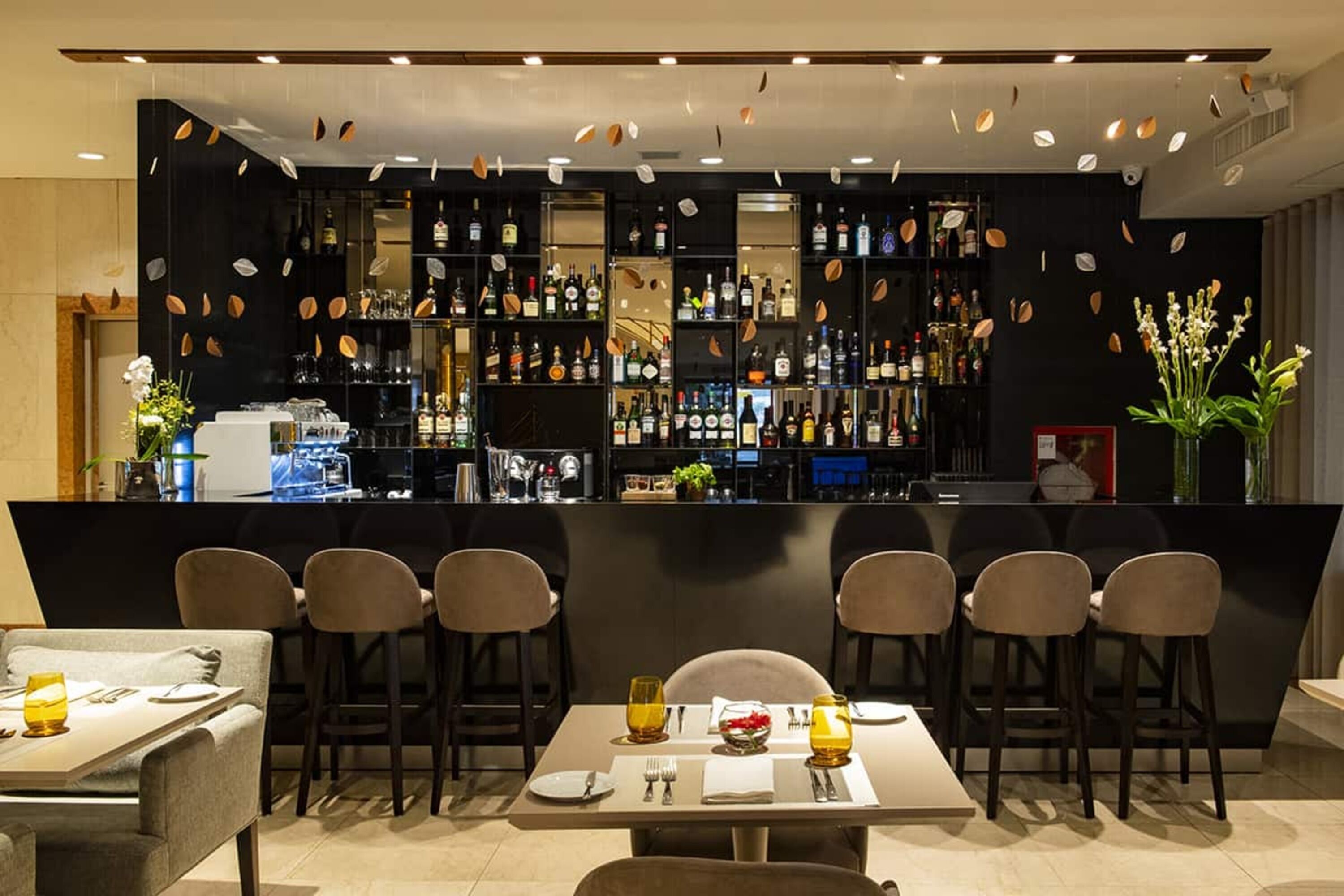 A bar area with multiple shelves of bottles, a counter, and bar stools.