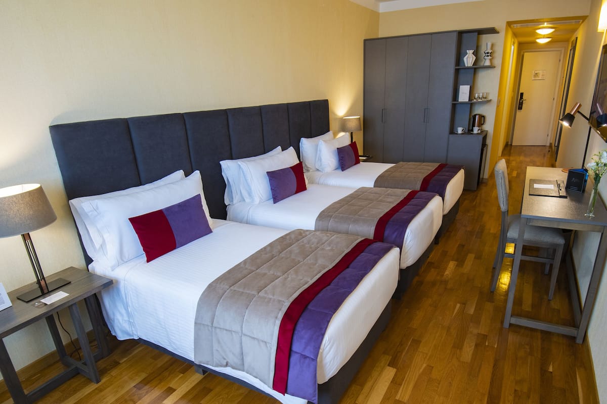 A hotel room with two beds, a desk, and a wardrobe.