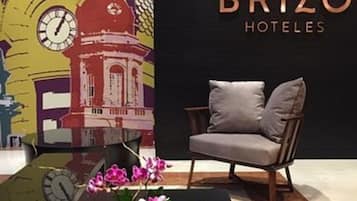 Een hotel lobby met een moderne bank, een klok en een decoratieve wand met een gebouw illustratie.
