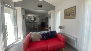 A red sofa in a bright room with a dining area in the background.