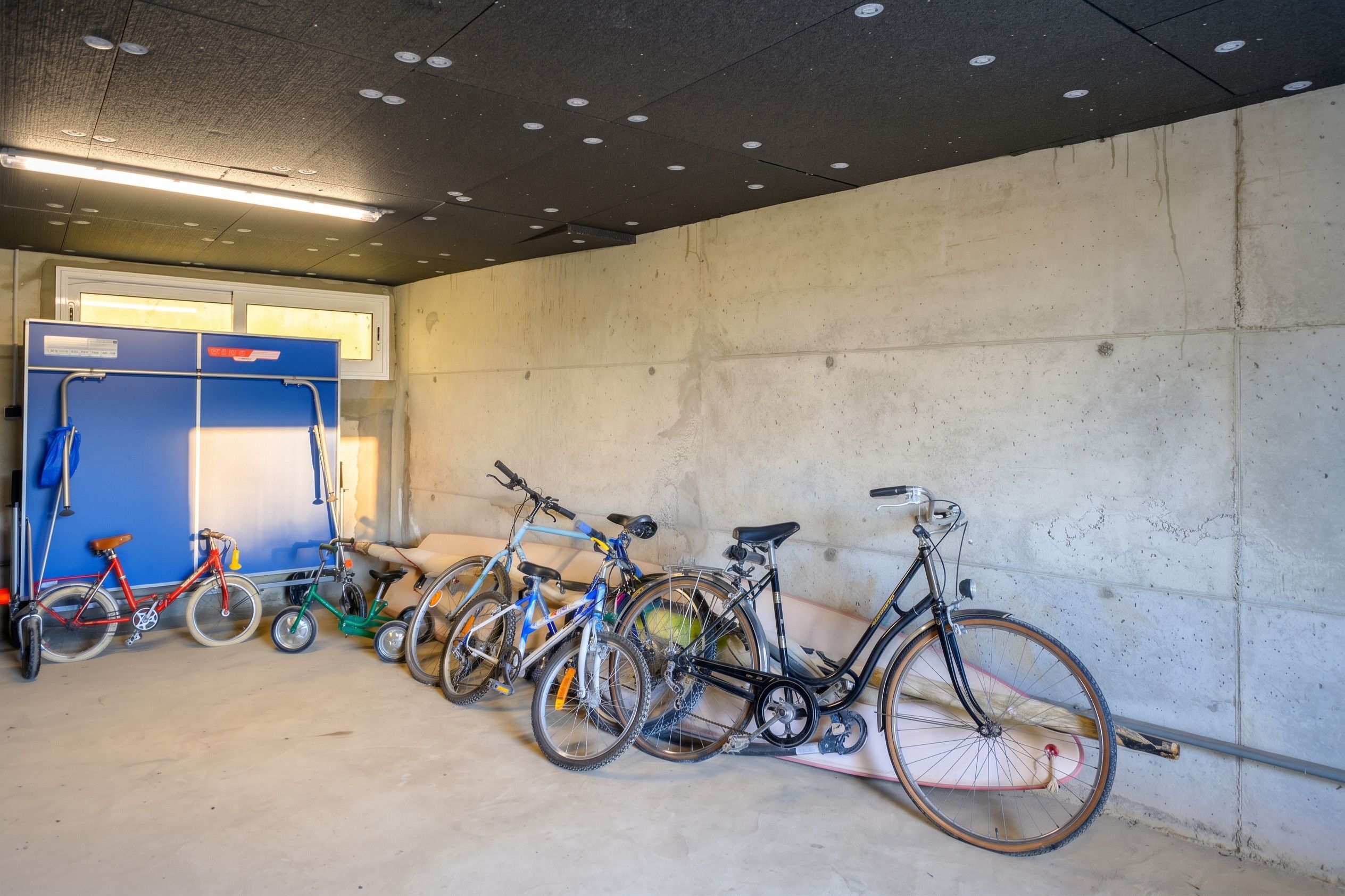Un aparcamiento con bicicletas estacionadas contra la pared.