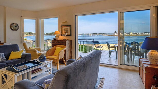 Un salon spacieux doté d’une grande porte-fenêtre coulissante donnant sur un balcon avec vue sur la mer.
