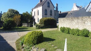 Un bâtiment en pierre, de style architectural traditionnel, qui se distingue par son entrée imposante et sa pelouse bien entretenue.