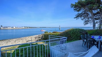 Un balcon avec vue sur la mer, un mur en pierre et une table avec des chaises.