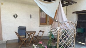 A wooden deck with a table and chairs, a wooden planter with flowers, and a wooden lattice structure.