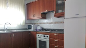 Una cocina con armarios de madera, microondas, tostadora, estufa y refrigerador.