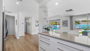 Una cocina moderna con suelo de madera, armarios blancos y una isla grande.