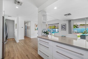 A modern kitchen with a wooden floor, white cabinetry, and a large island.