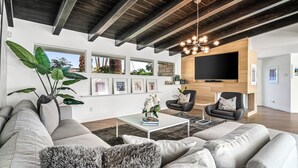 Una sala de estar moderna con un sofá modular, una mesa de centro, una chimenea y un televisor grande.