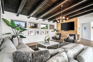 A modern living room with a sectional sofa, a coffee table, a fireplace, and a large TV.