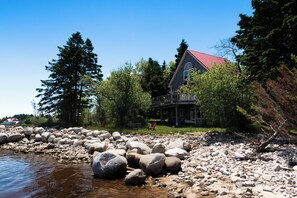 Escape to a serene lakeside retreat surrounded by lush greenery and a well-maintained lawn.