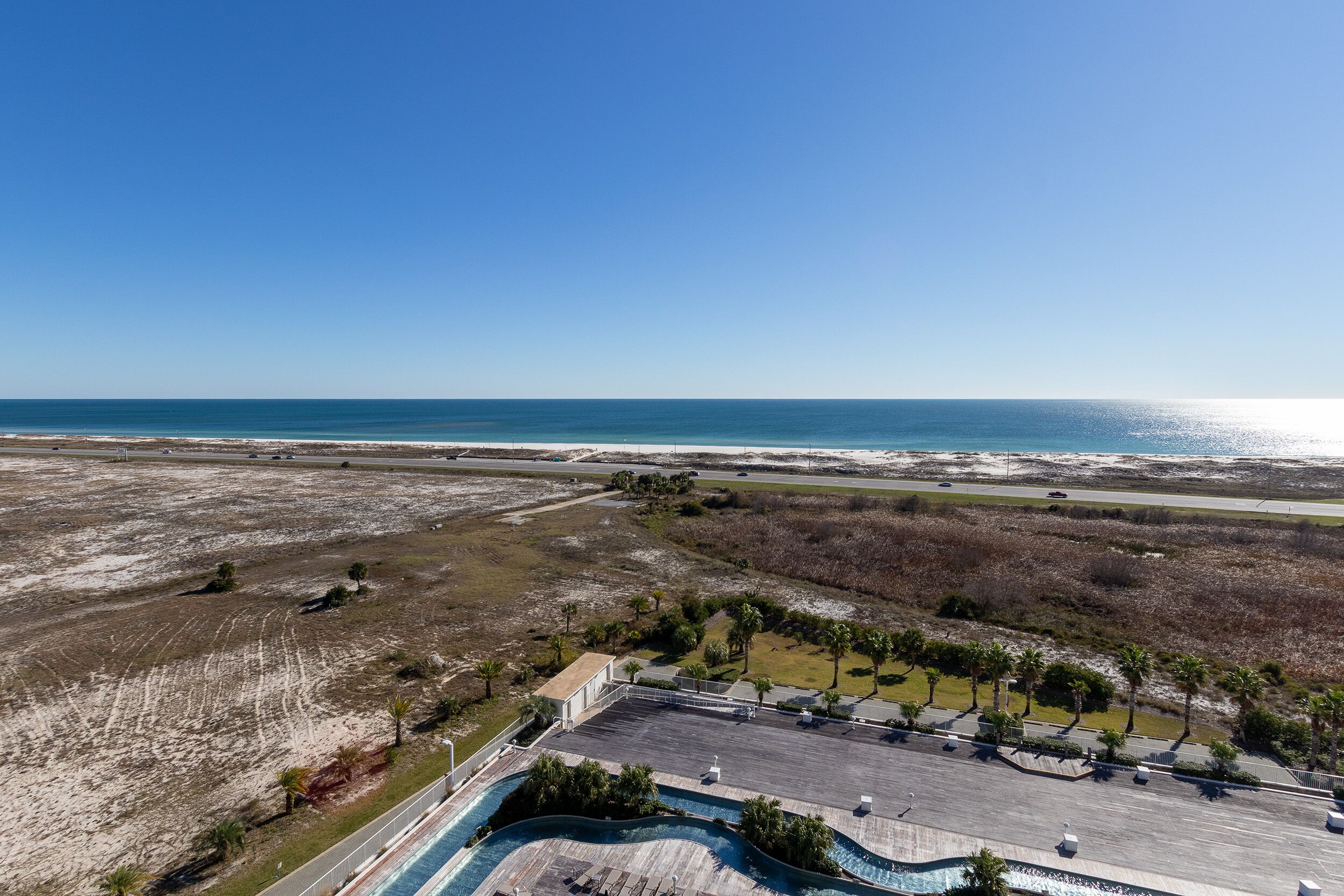 Ein Resort mit großem Pool, Blick auf den Strand und einem Parkplatz.