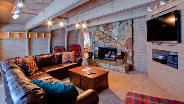 Ein gemütliches Wohnzimmer mit einer Ledersofa, einem Kamin, einem Fernseher und einer Wand mit Steinverkleidung.