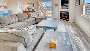 A spacious living room with a large sectional sofa, a coffee table, and a fireplace. - Oceanview Dog Friendly Home with Private Pool, Hot Tub, Game Room, and Wet Bar (Buxton)