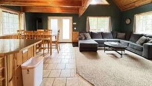 A cozy cabin interior with a dining area, a sofa, and a kitchen. - 24 MI to YNP | ATV Trails | Near Big Springs (Island Park)
