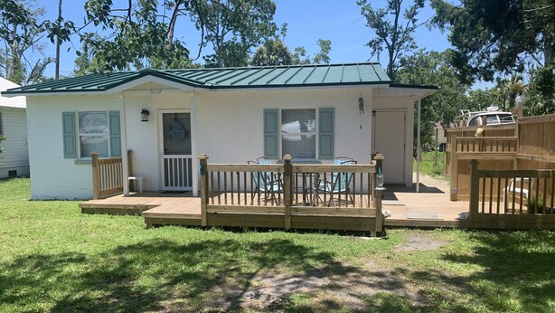 A small, single-story mobile home with a green roof, a porch with a wooden railing, and a small deck area. - Coastal Charm!!!! Super cute and clean!! (Port St Joe)